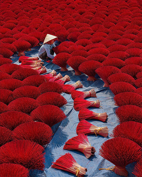 "The woman is drying sticks of incense, a step in producing incense. In Vietnam."